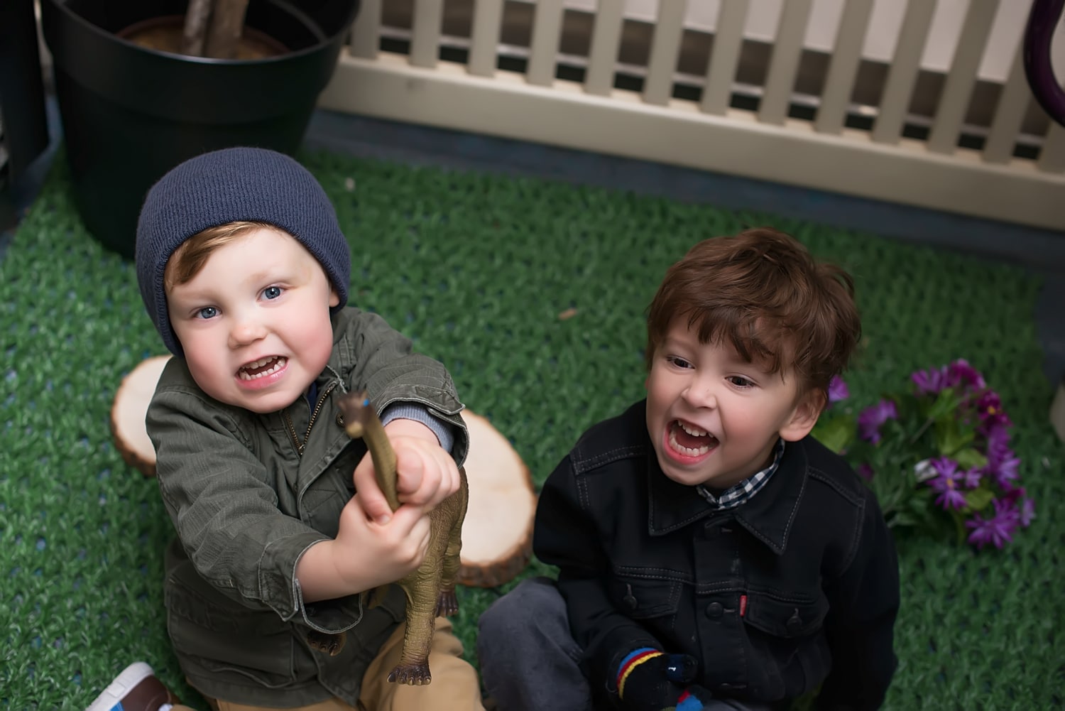 Two Kinderberry Hill boys playing with a toy dinosaur in the outdoor playground.